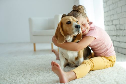 A small child hugs her dog.